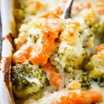 Close-up of a cheesy vegetable casserole with baby carrots, broccoli, and cauliflower in a white baking dish