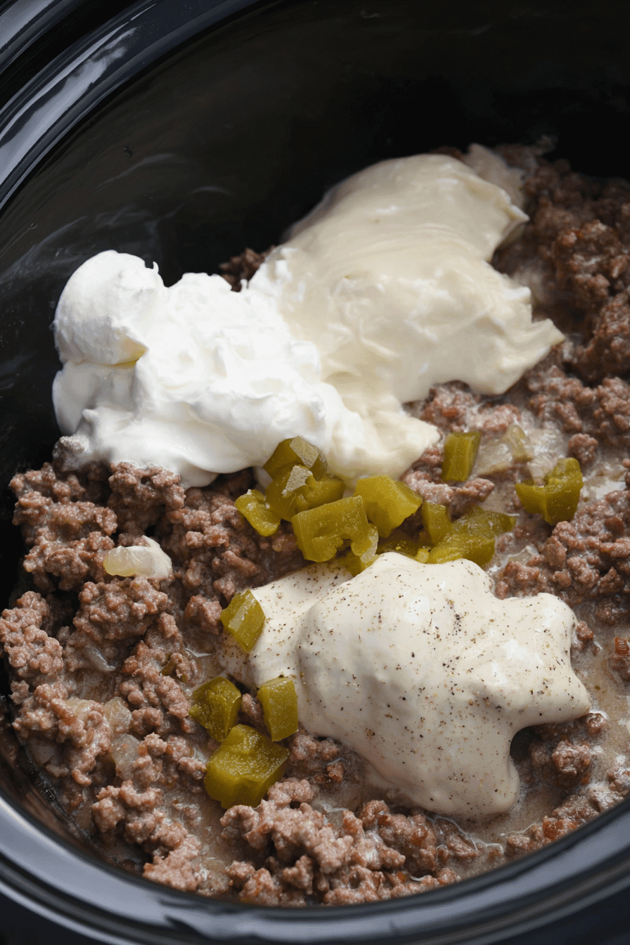 Ground beef in a slow cooker topped with cream of mushroom soup, sour cream, diced green chilies, and spices.