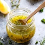 Herby Lemon Vinaigrette in glass jar with herbs and lemon