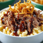 Bowl of brisket mac and cheese topped with crispy fried onions and BBQ sauce