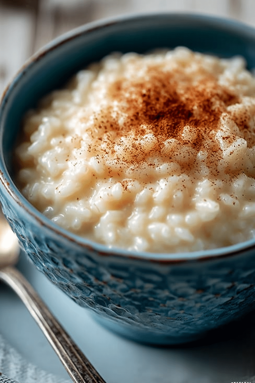 Creamiest rice pudding in a rustic blue bowl, topped with cinnamon and glowing in soft natural light