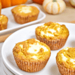 Keto pumpkin cream cheese muffins with swirled tops on a white plate, perfect for fall baking.