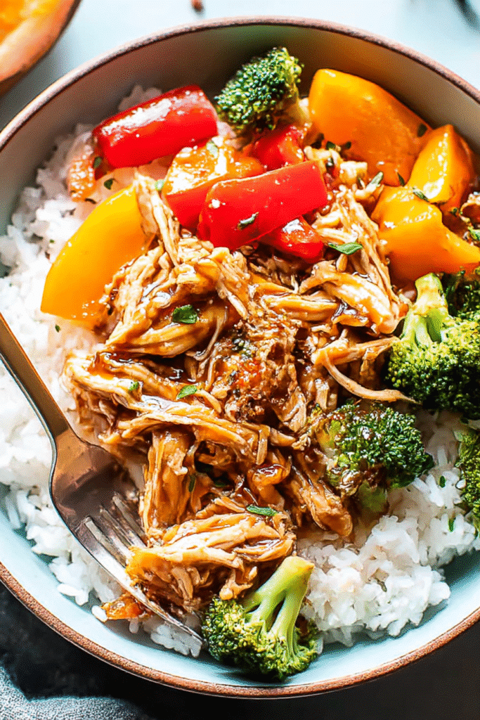 Easy crock pot teriyaki chicken with rice, broccoli, and peppers in a bowl with fork ready to eat.