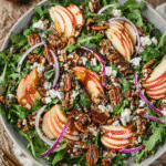 Fresh apple arugula salad with pecans, feta, red onions, and balsamic drizzle in a rustic ceramic bowl.