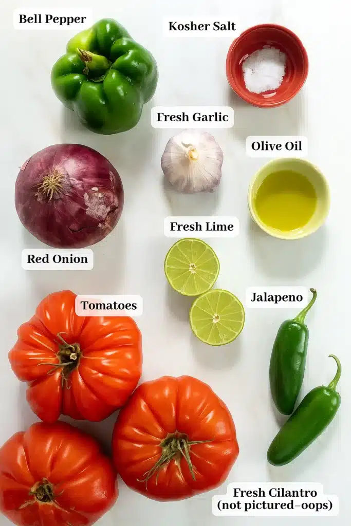 Labeled ingredients for fresh tomato salsa including tomatoes, bell pepper, red onion, garlic, lime, jalapeños, olive oil, and salt on white surface.