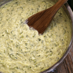 Creamy zucchini sauce in a skillet with wooden spoon, showing smooth and chunky texture