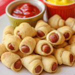 Golden-brown hot dog nuggets served with ketchup and mustard on a white plate.
