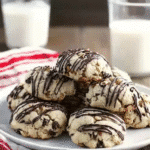 Homemade Italian Christmas cookies drizzled with dark chocolate on a white plate, served with milk and holiday linens