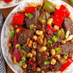 Kung Pao Beef with bell peppers, peanuts, and rice in a white bowl