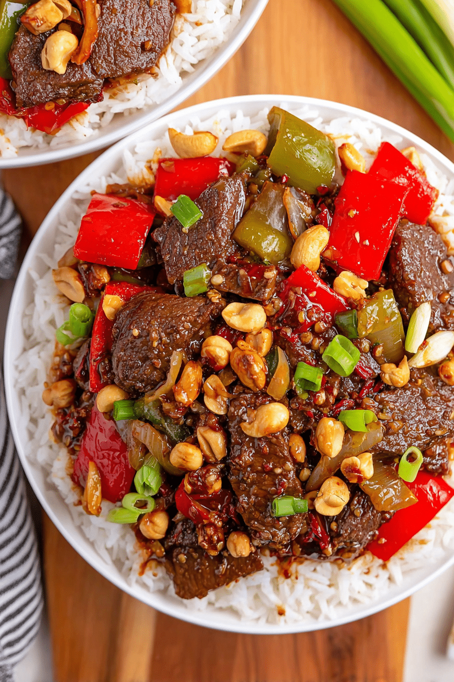 Kung Pao Beef with bell peppers, peanuts, and rice in a white bowl