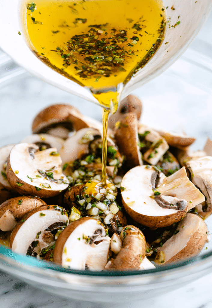Garlic herb marinade being poured over mushrooms for grilled garlic mushroom skewers.