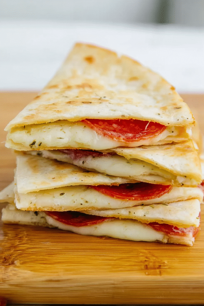 Lunchbox filled with pepperoni pizzadillas, marinara sauce, blueberries, and strawberries for a balanced, kid-friendly meal.