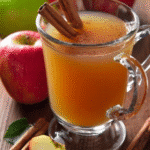 Warm mulled cider in a glass mug with cinnamon sticks and apples, styled for a cozy crockpot cider presentation