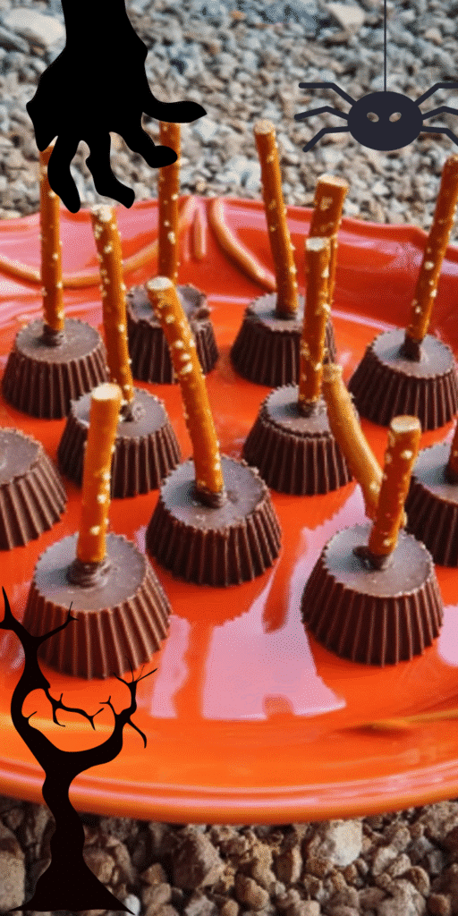 Mini chocolate Witch’s Broomsticks made from peanut butter cups and pretzels on an orange plate.