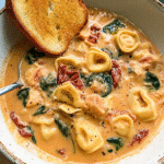 Creamy Marry Me Chicken Soup with tortellini, sun-dried tomatoes, spinach, and chicken in a rich tomato cream broth, served with toasted bread.