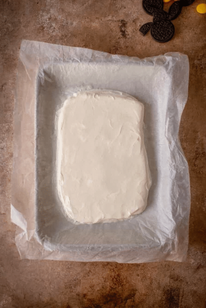 Melted white chocolate spread on parchment paper to make White Chocolate Halloween Oreo Bark