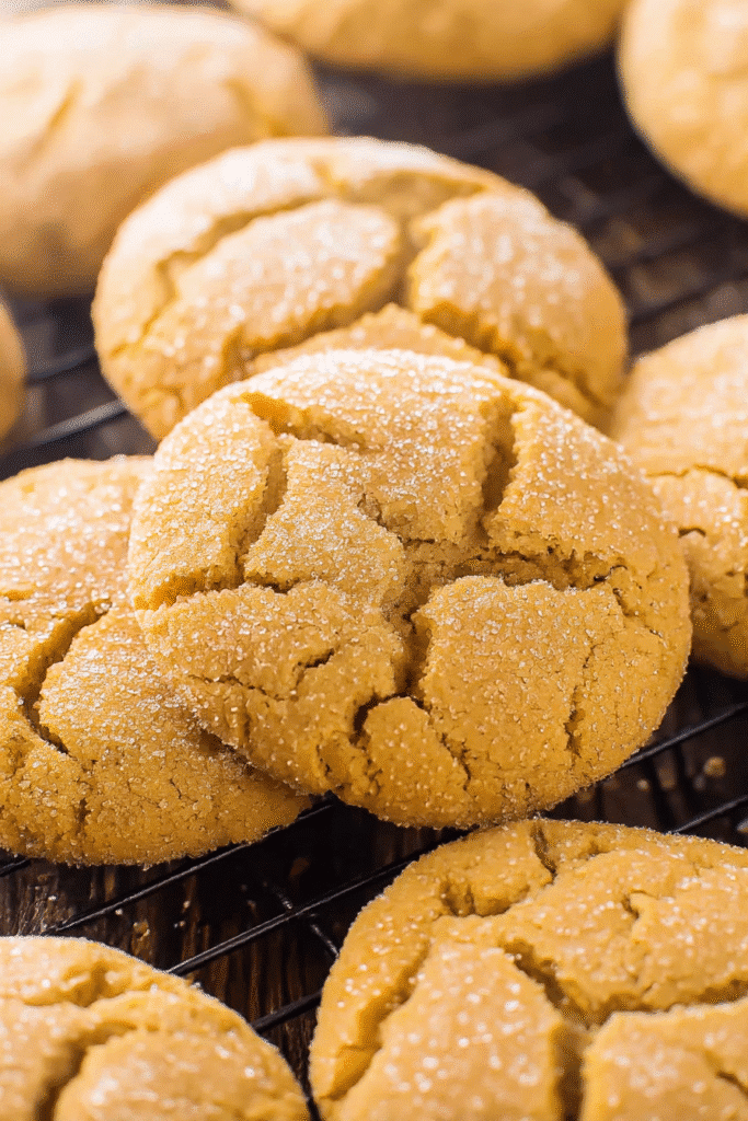 Crackled pumpkin sugar cookies with golden sugar coating on a wire rack
