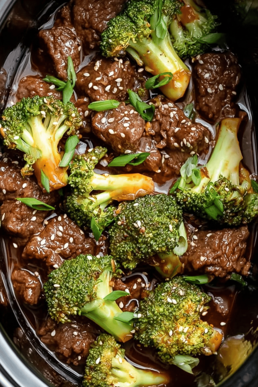 Slow cooker beef and broccoli in rich sauce with sesame seeds and green onions.