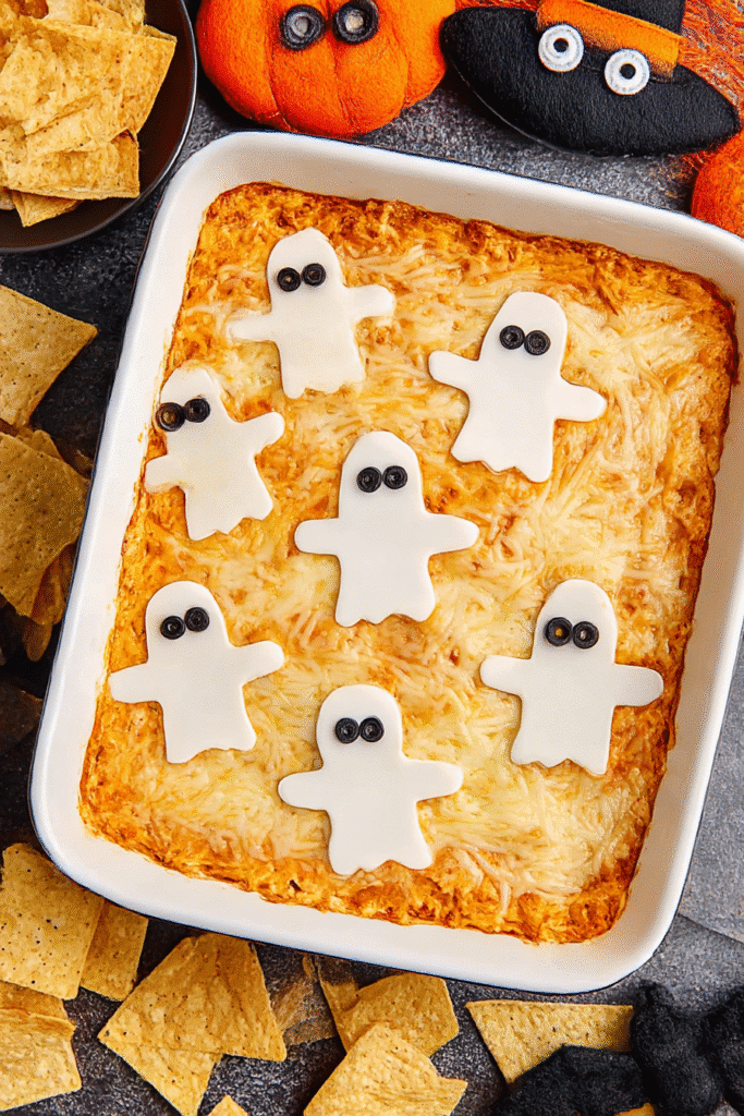 Halloween Buffalo Chicken Dip topped with ghost-shaped cheese slices and served in a white baking dish.