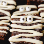 Halloween mummy brownies with candy eyes and white frosting bandages.