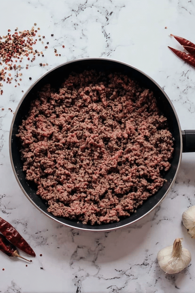 Browning ground beef in a skillet for slow cooker chili.
