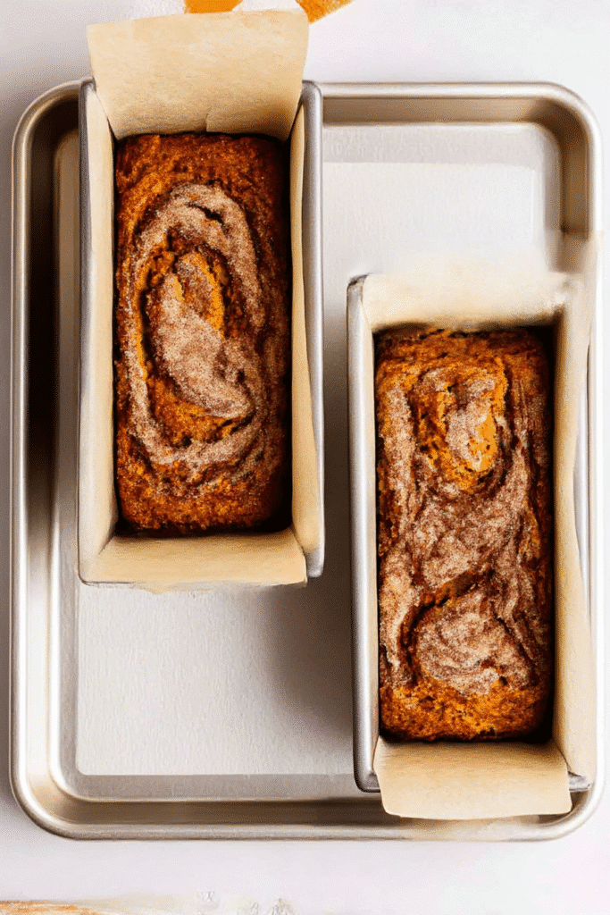 Two mini loaves of cinnamon swirl pumpkin bread in baking pans, ready for the oven.