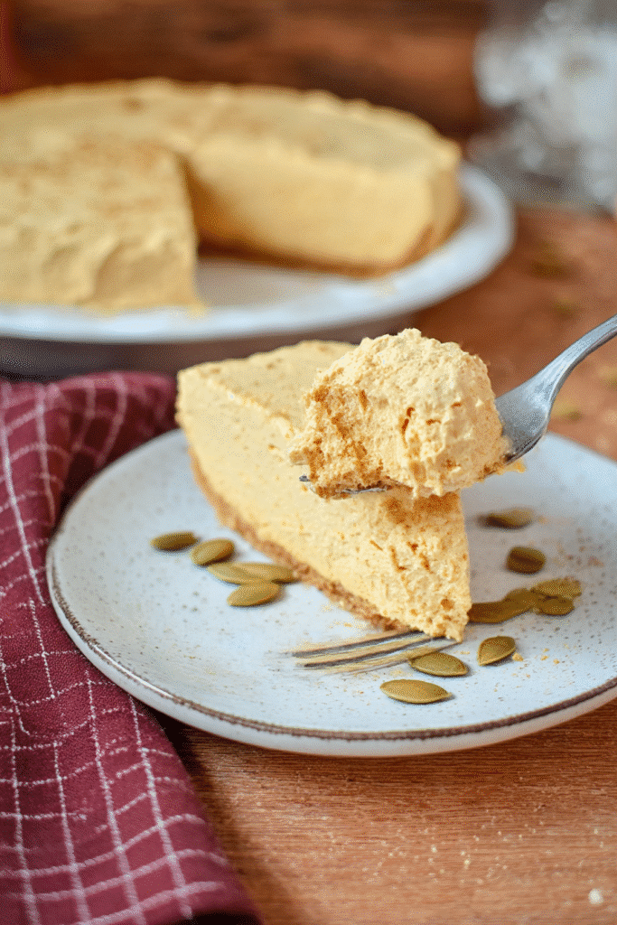 A fluffy bite of Pumpkin Fluff Pie takes center stage in this cozy close-up, showcasing its airy, whipped pumpkin filling.