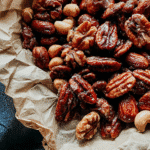 Caramelized Dragon Roasted Nuts mix with pecans, almonds, and peanuts on rustic parchment paper.
