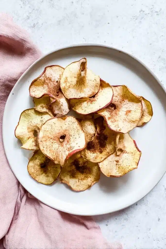 crispy air fryer apple chips on white plate with cinnamon