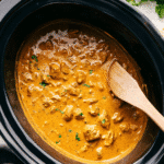 Creamy Crockpot Butter Chicken in a slow cooker with rice, cilantro, and naan bread.