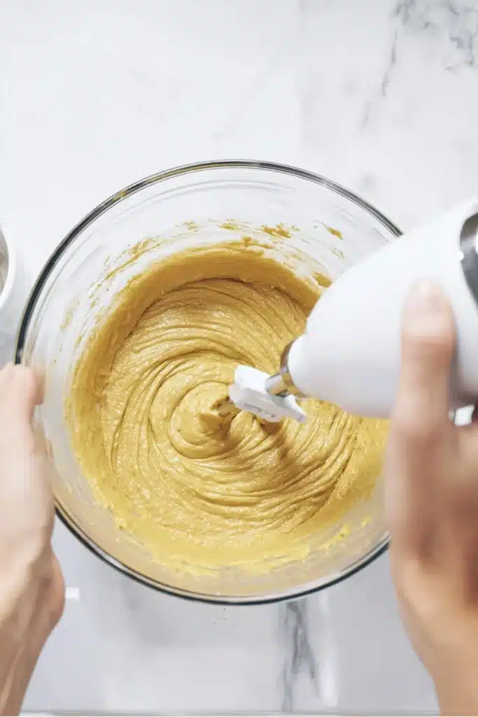 mixing easy pumpkin bread batter with hand mixer in glass bowl