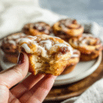 Hand holding a Cinnamon Roll Apple Pie with gooey apple filling