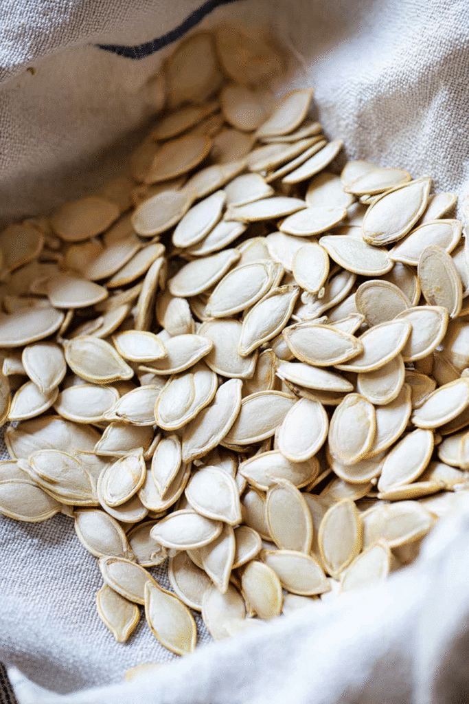 Pumpkin seeds recipe preparation with fresh raw seeds drying on a kitchen towel.