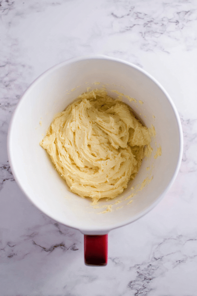 Creamed butter and sugar mixture in a white mixing bowl, first step in making pumpkin tiramisu cookies.