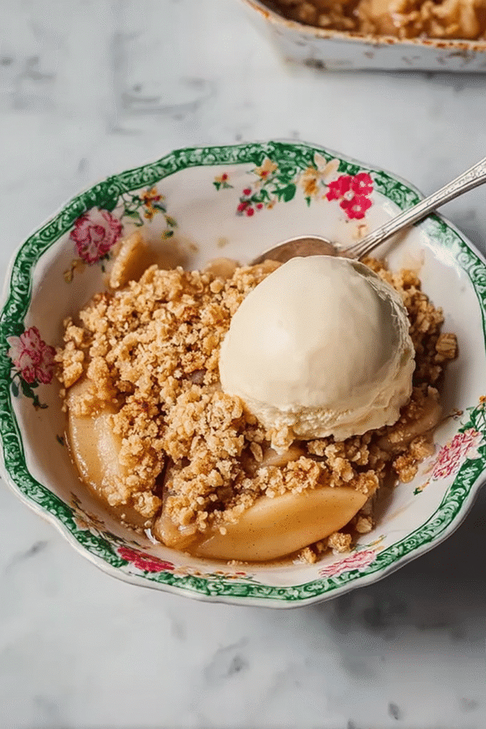 Simple apple crumble served in a floral bowl with vanilla ice cream.