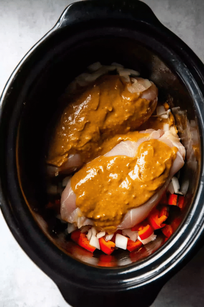 Raw chicken with peanut sauce in slow cooker