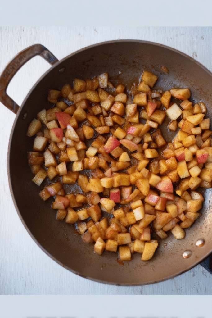 diced apples cooking with sugar and cinnamon in a skillet for mini apple pies