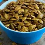 Air fryer pumpkin seeds in a white bowl on wooden table