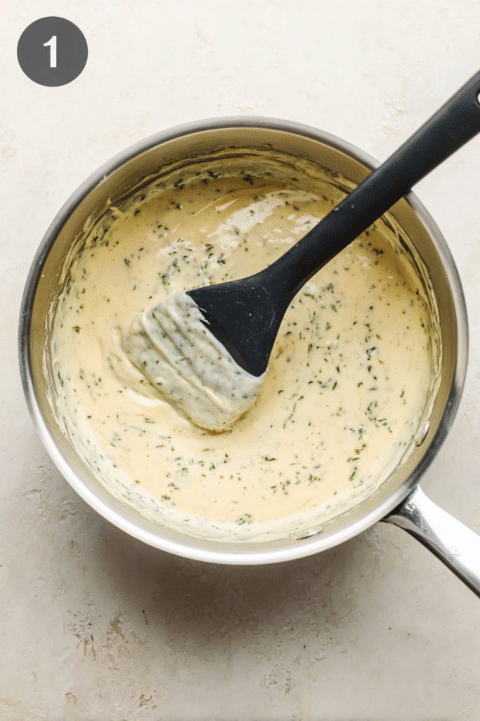 creamy scalloped potatoes sauce being stirred in saucepan