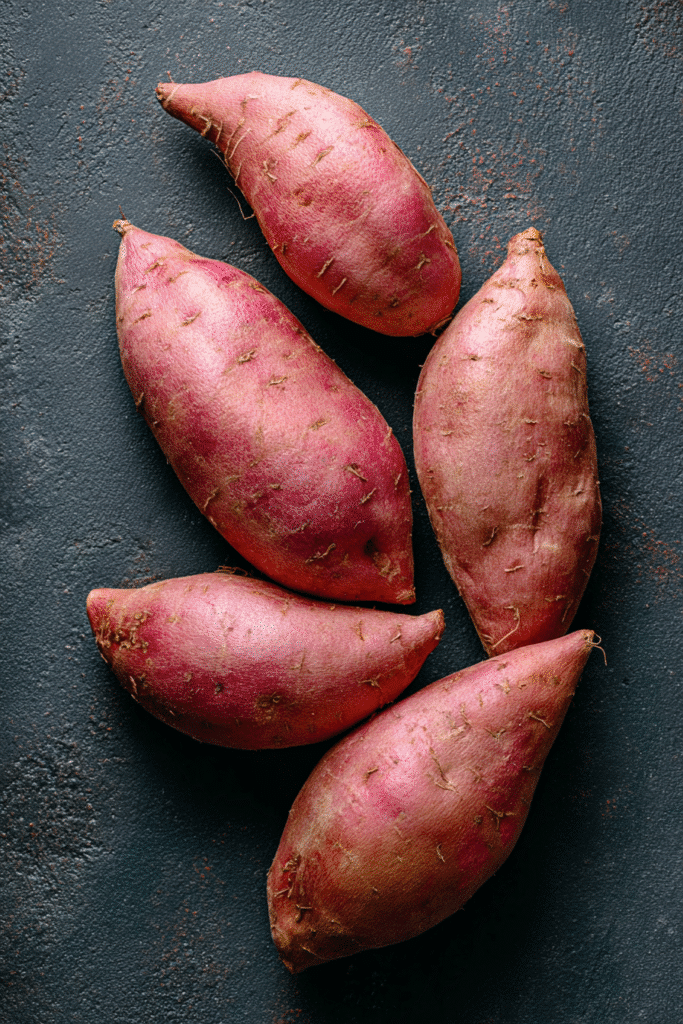 Raw sweet potatoes for southern maple sweet potato casserole on dark background