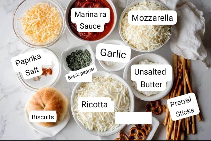 Pizza-stuffed pumpkin ingredients flat lay: biscuits, mozzarella, ricotta, marinara sauce, pretzel sticks, butter, garlic, and spices.