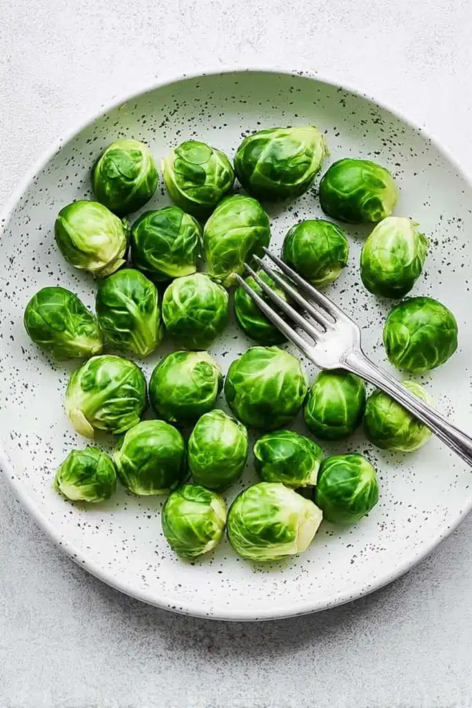 fresh raw brussels sprouts in speckled bowl