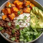 Sweet potato taco bowl. Bowl with rice, seasoned beef, avocado, cilantro, and sour cream.