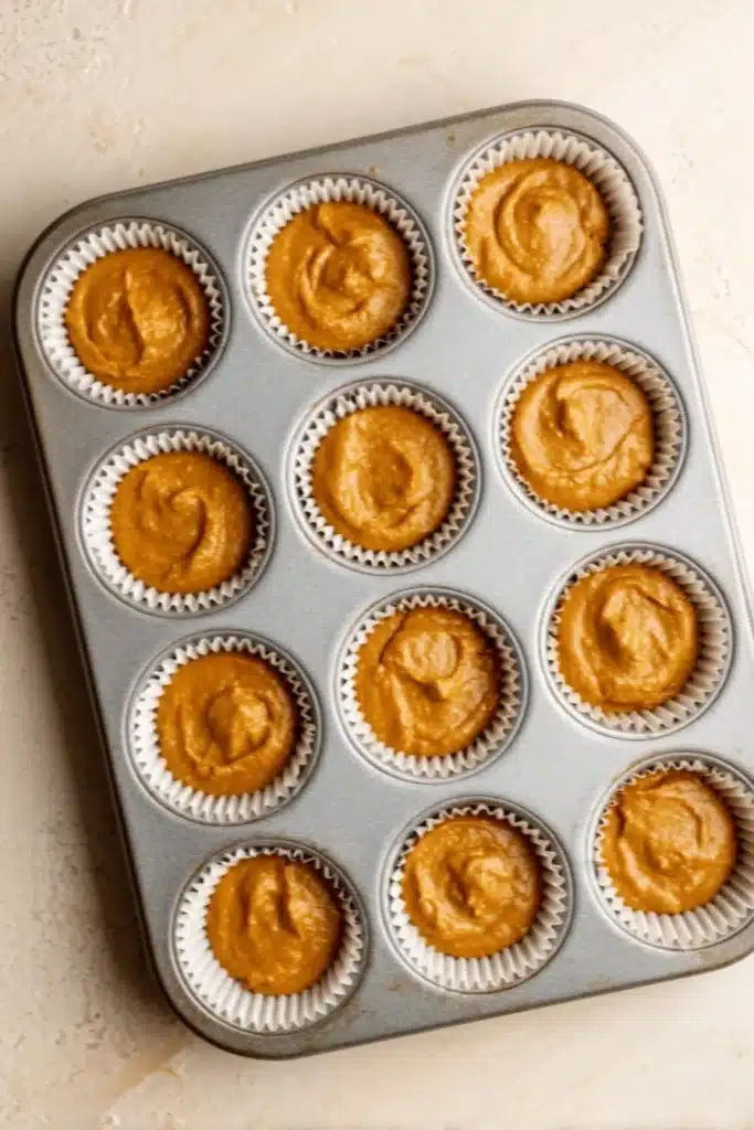 Raw pumpkin cupcake batter in muffin tin ready for baking