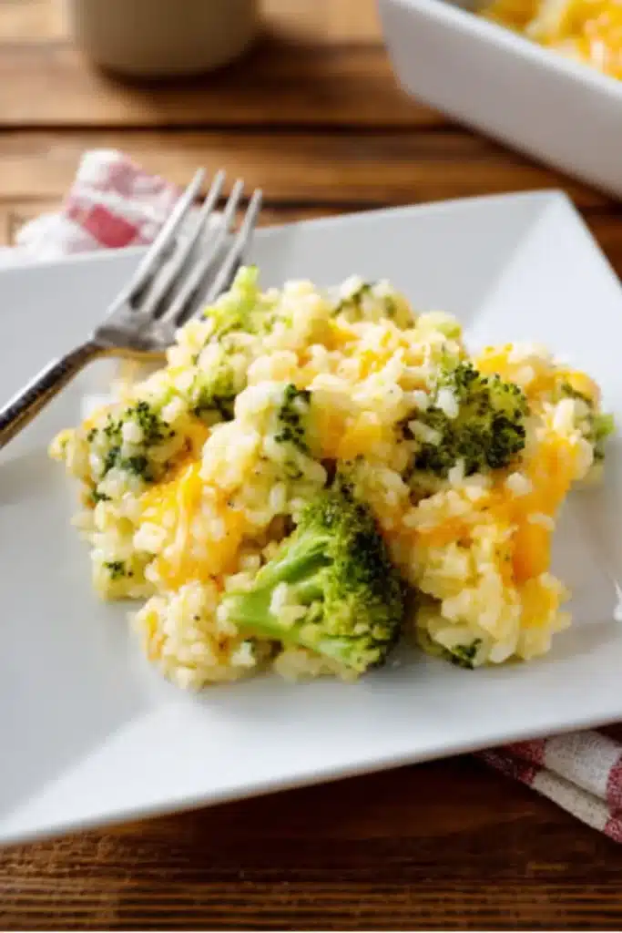 Spoonful of cheesy broccoli rice casserole above plated serving