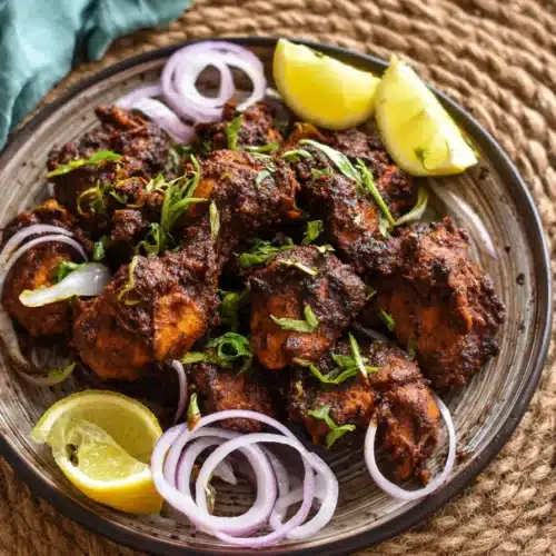 flavorful chicken chukka with onion rings and lemon on a plate