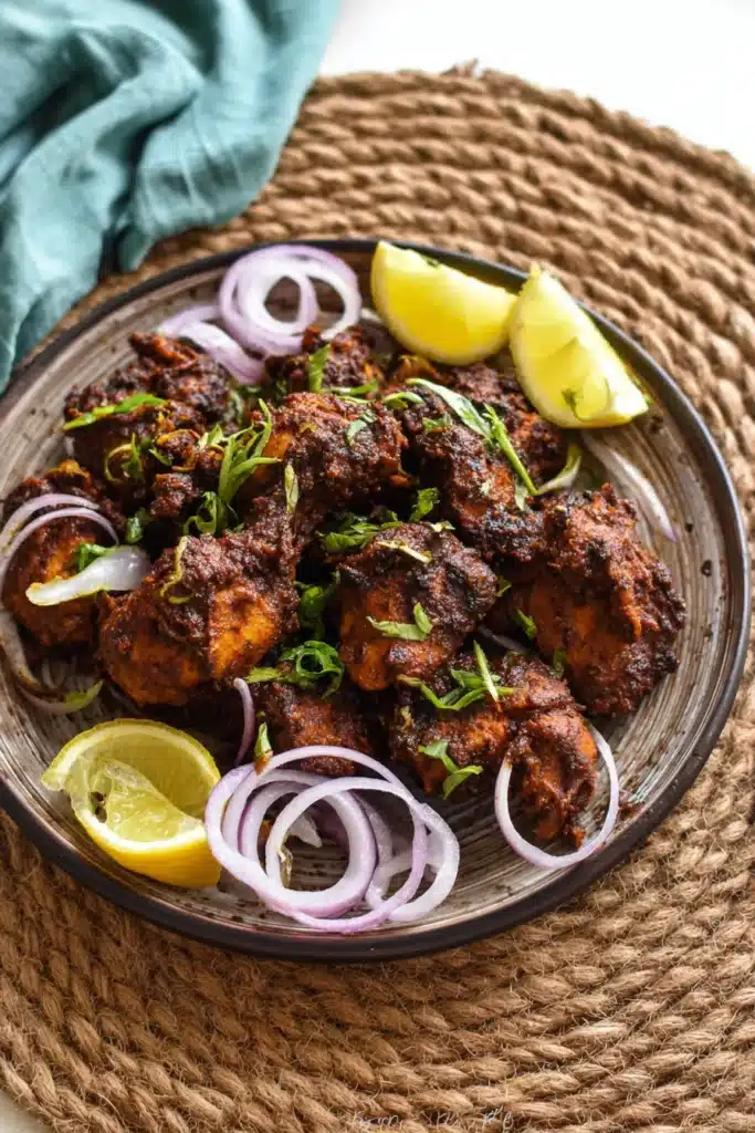 flavorful chicken chukka with onion rings and lemon on a plate