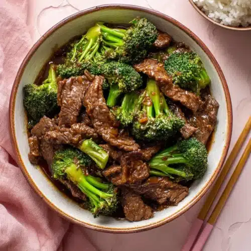 Chinese beef and broccoli in garlic soy sauce with rice on pink background