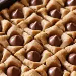 Close-up of peanut butter blossom bars topped with chocolate drops in a baking pan