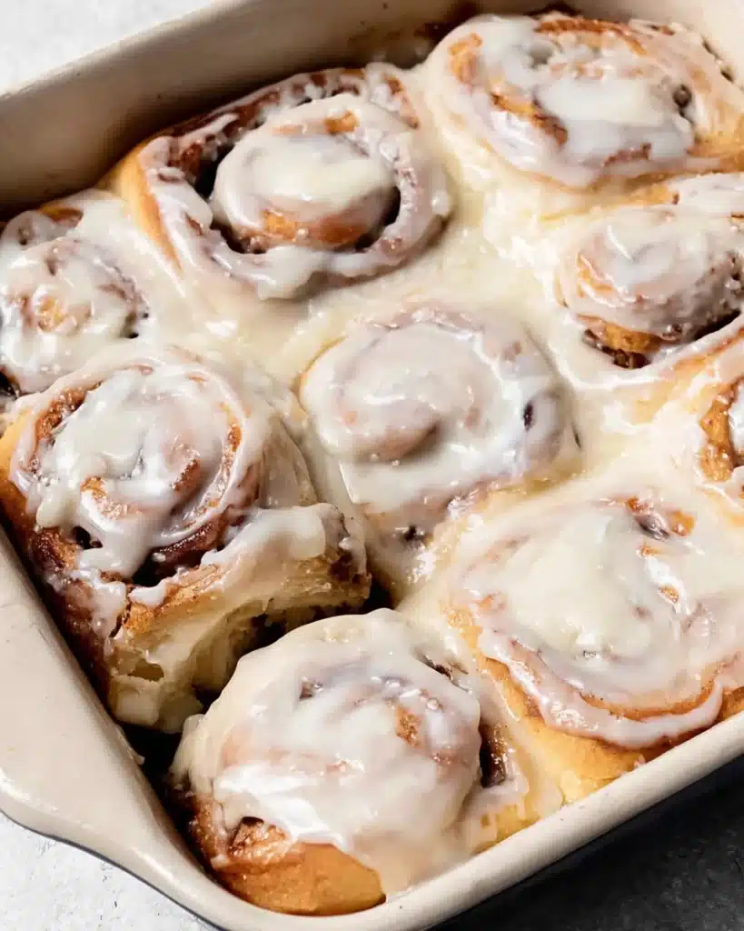 pulling apart gooey homemade cinnamon rolls with icing